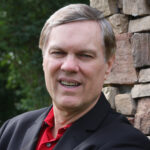 A man in a black jacket and red shirt