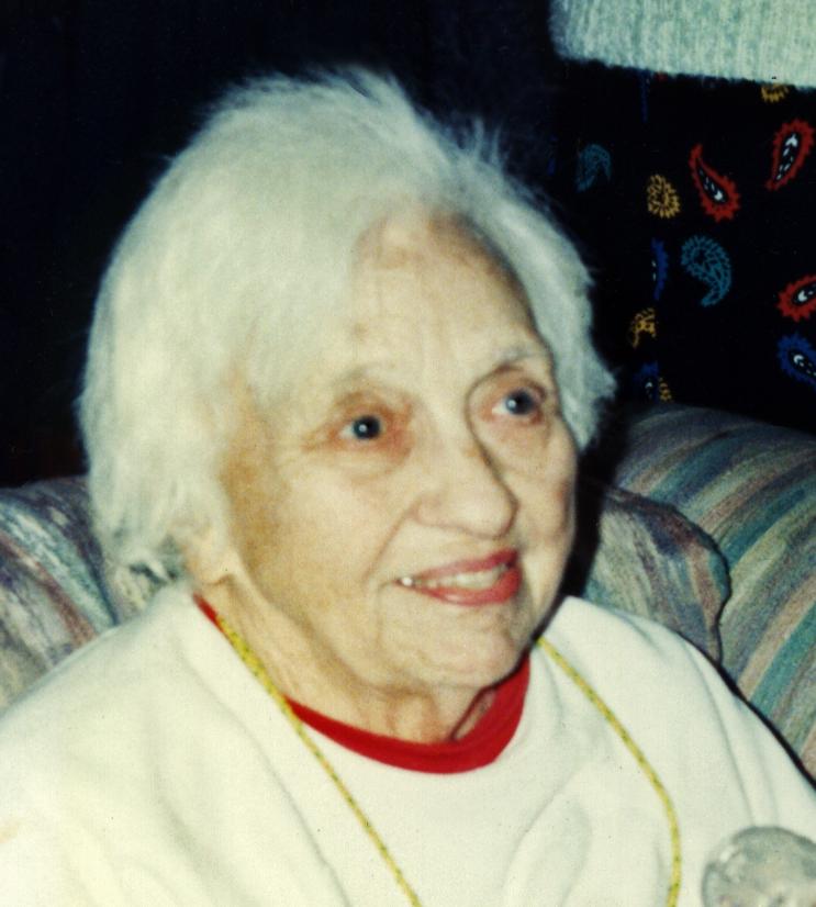 Elderly woman smiling on a couch.