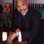 A man in a suit and tie holding his watch.