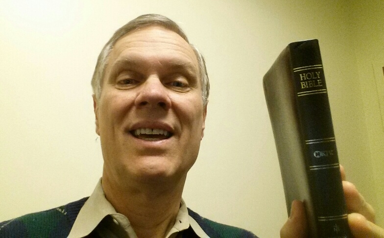 Person smiling while holding a Bible.