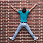 A man is jumping in the air on a brick wall.