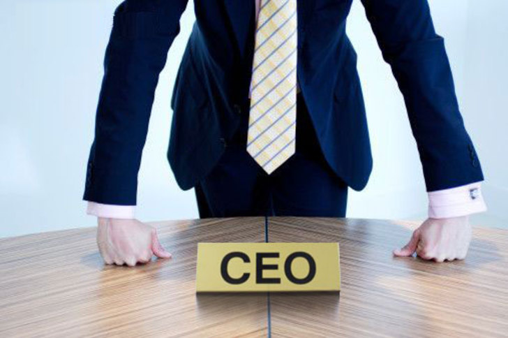 A man in a suit and tie standing at the head of a table.