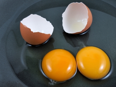 Broken eggshells beside yellow egg yolks.