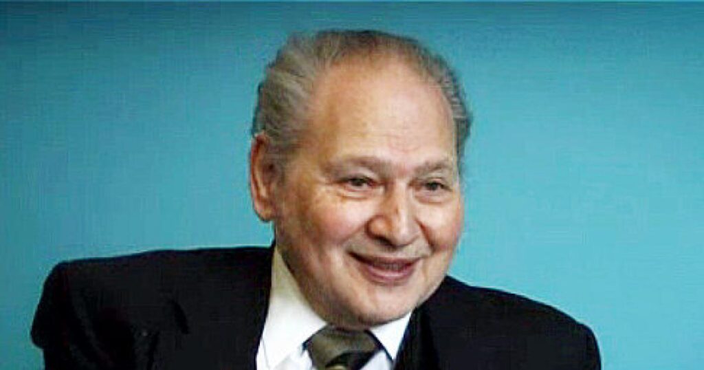 Smiling elderly man in a suit.