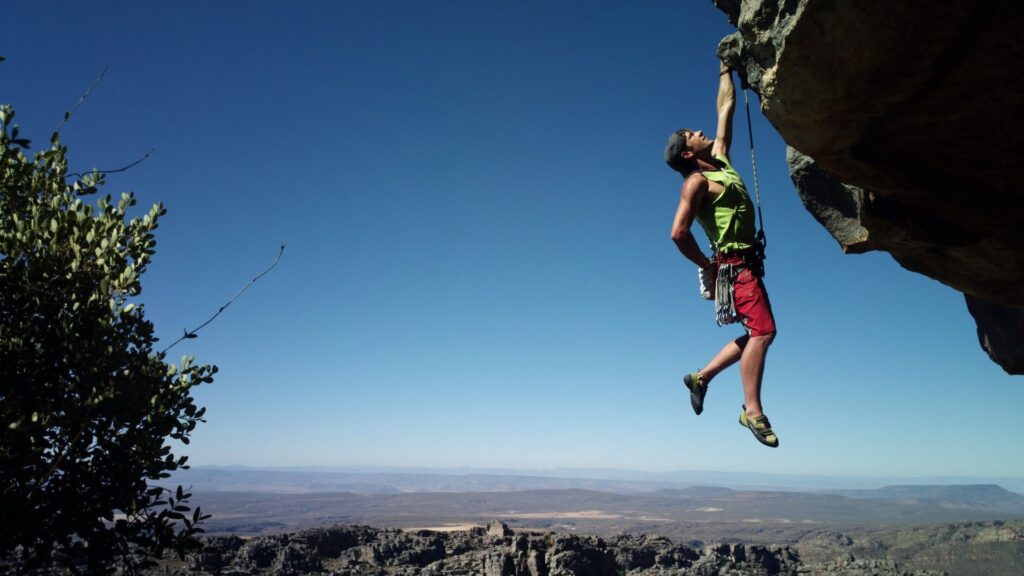 Climber hanging from a rock under clear sky.