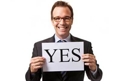 Smiling man holding "YES" sign.