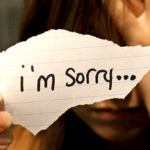 Person holding a note saying "I'm sorry."