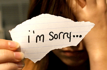 Person holding a note saying "I'm sorry."