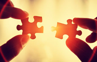 Hands holding two puzzle pieces together.