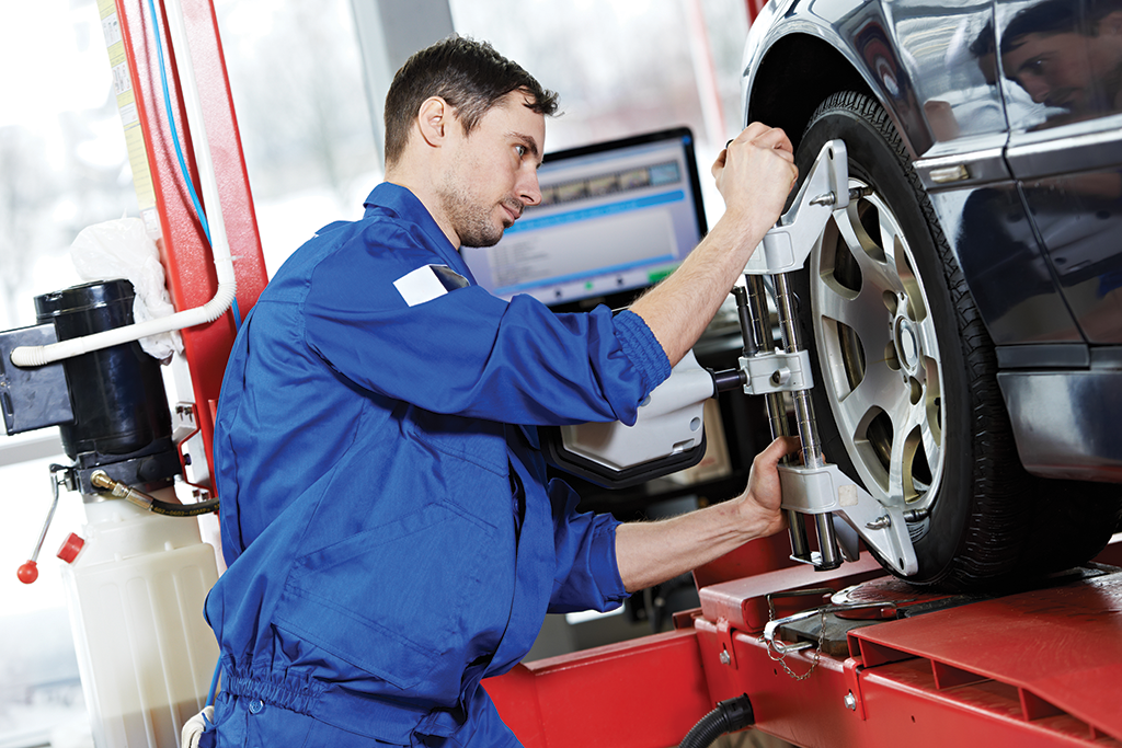 Mechanic performing tire alignment on a vehicle.