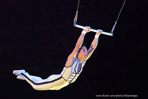 Aerialist performing on trapeze bars.