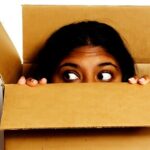 Person peeking out of a cardboard box.