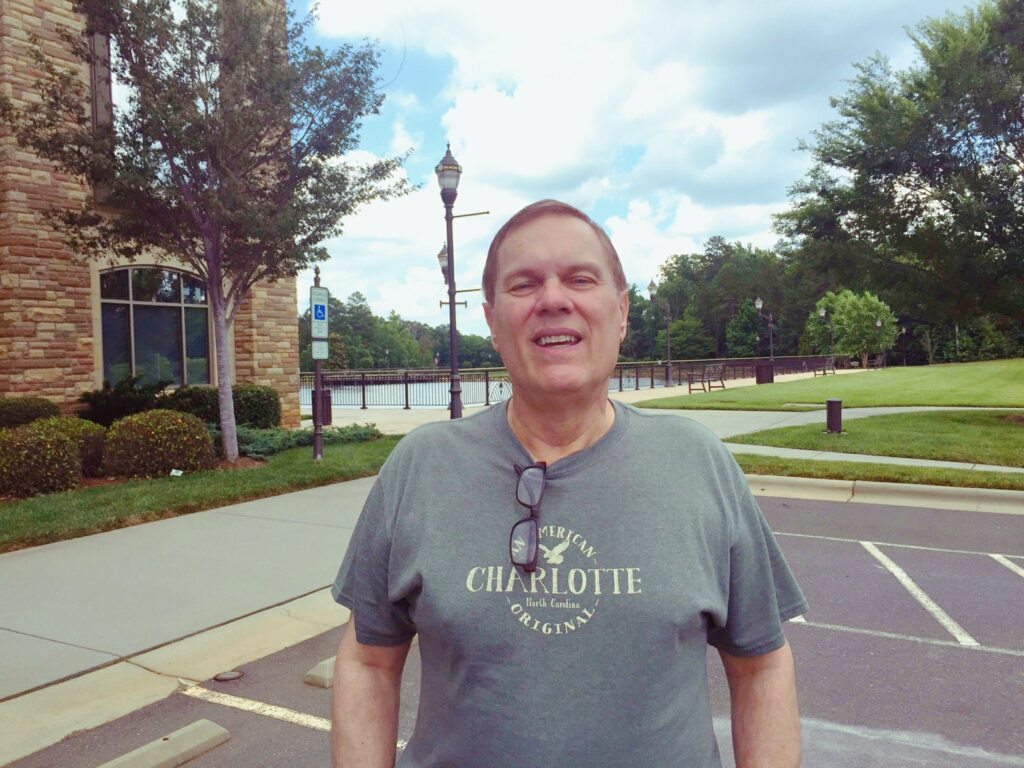 Smiling man standing outdoors near water.