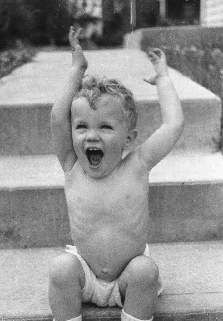 Laughing child with arms raised in excitement.