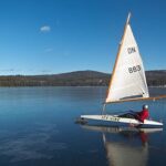 Sailboat gliding across frozen lake surface.