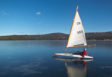 Sailboat gliding across frozen lake surface.