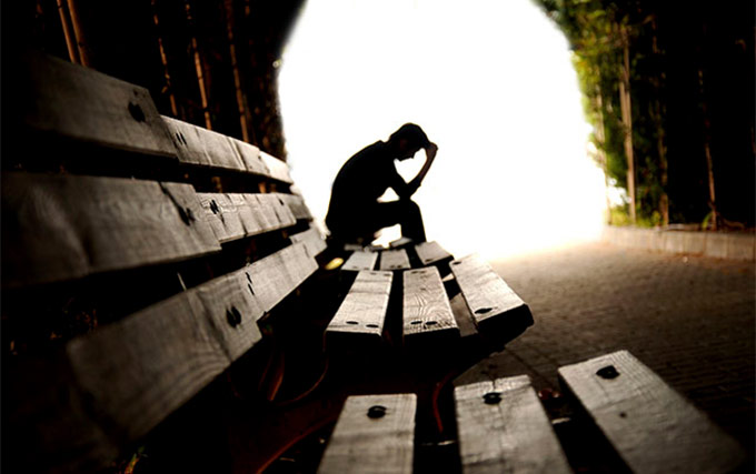 A person sitting on top of a wooden bench.