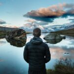 Person gazing at a serene mountain reflection.