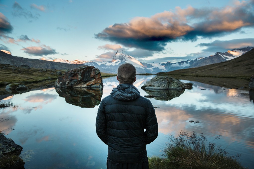 Person gazing at a serene mountain reflection.