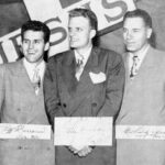 Three men posing with signatures, black and white.