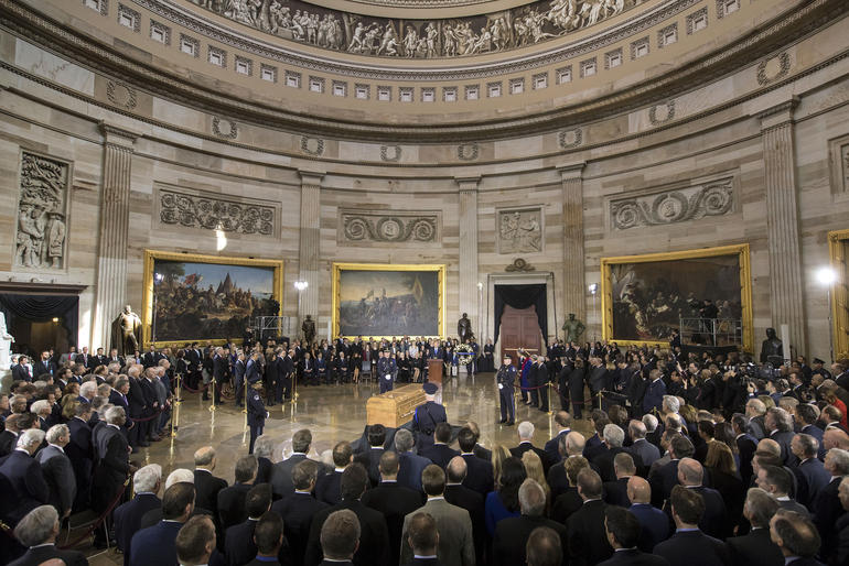 Ceremony with crowd surrounding a casket.