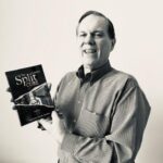 Man holding book titled "The Split Cure."