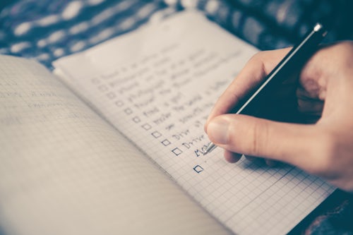 Hand writing a checklist in notebook.