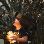 Child holding a glowing jar in nature.