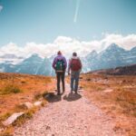 Couple walking on mountain trail together.