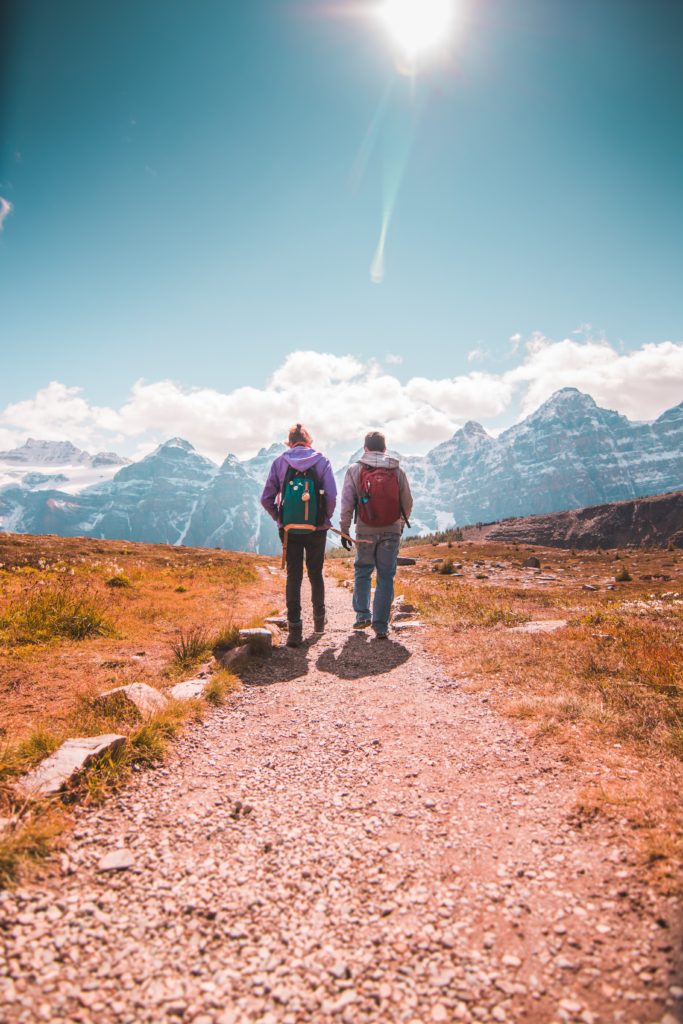 Couple walking on mountain trail together.