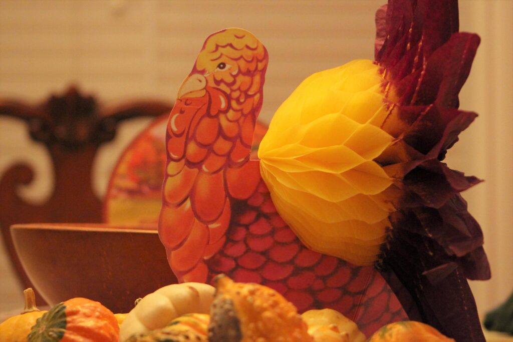 Colorful turkey decoration among autumn gourds.