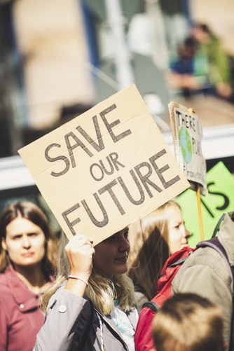 A woman holding up a sign that says " save our future ".