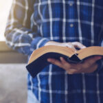 Person holding an open book indoors.