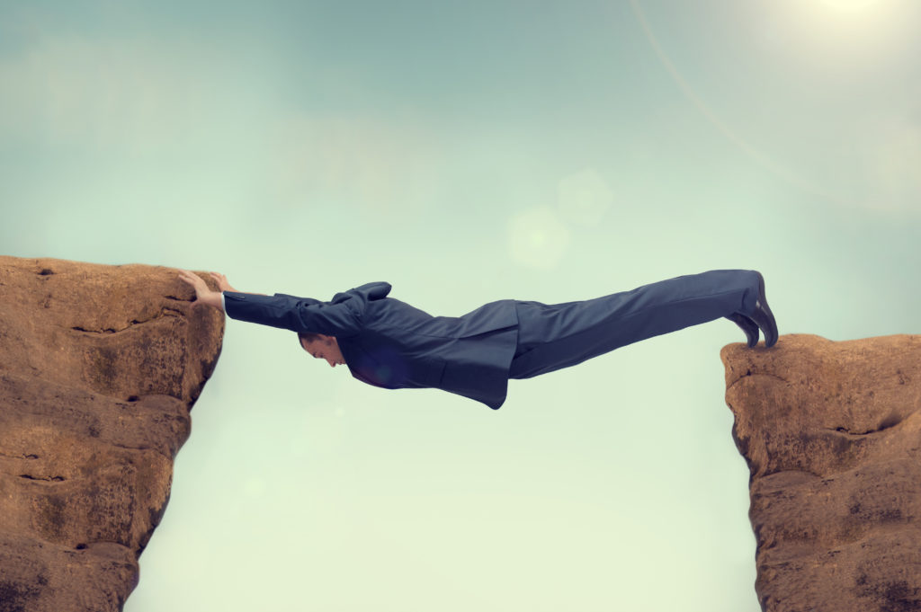 A man in a suit is climbing over two rocks.