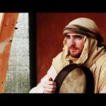 Man in traditional attire holding a drum.