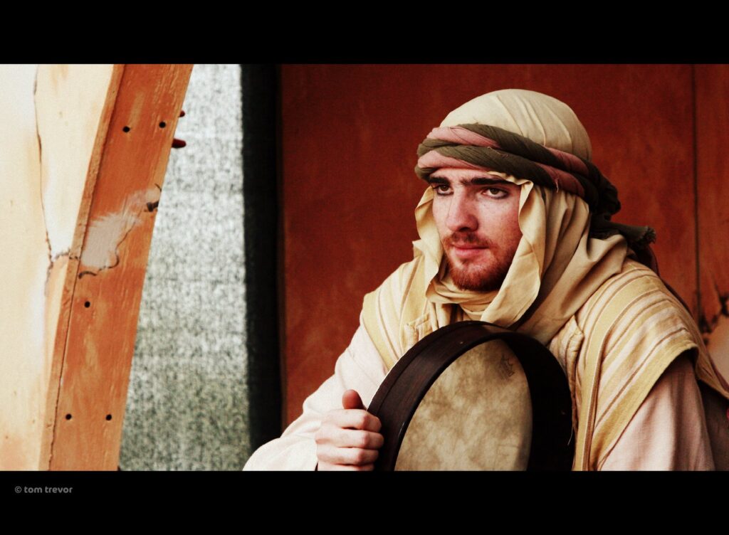 Man in traditional attire holding a drum.