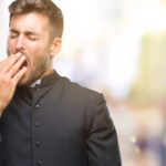 Man in a black outfit yawning.