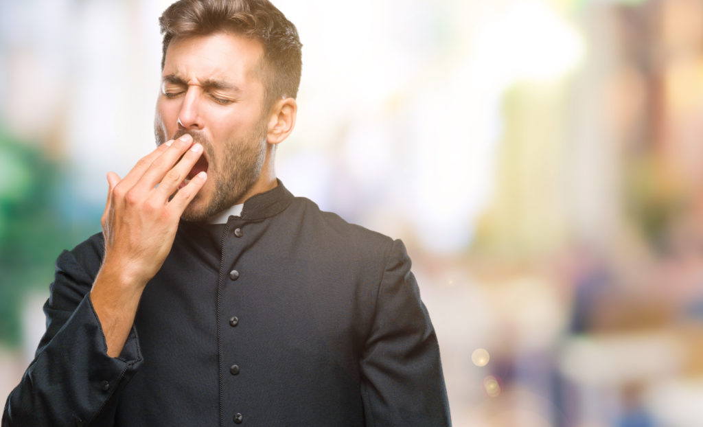 Man in a black outfit yawning.