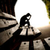 A person sitting on top of a wooden bench.