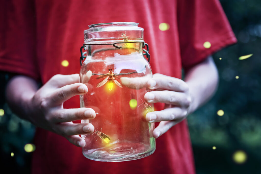 Child holding a jar of glowing fireflies.