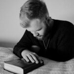 Man resting head on book, contemplative mood.