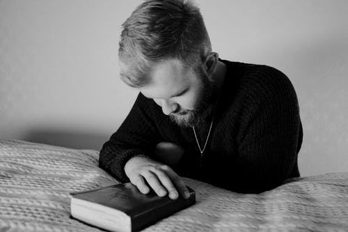 Man resting head on book, contemplative mood.