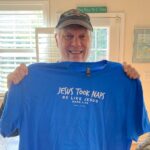 Man holding blue shirt with playful text.