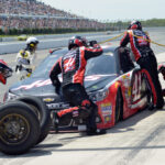 NASCAR pit stop with crew changing tires.