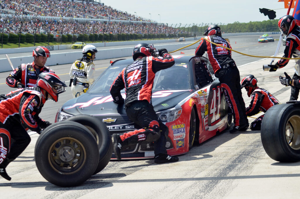 NASCAR pit stop with crew changing tires.