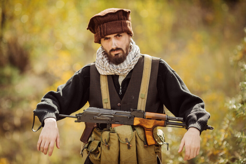 Bearded man with rifle in autumn setting.