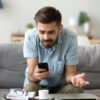 A man sitting on the ground looking at his phone.