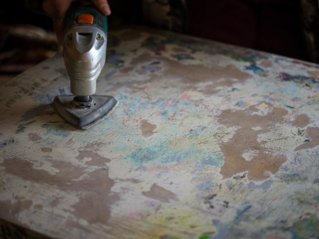 A person using an electric sander on a painting.