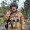 A man in military gear giving the peace sign.